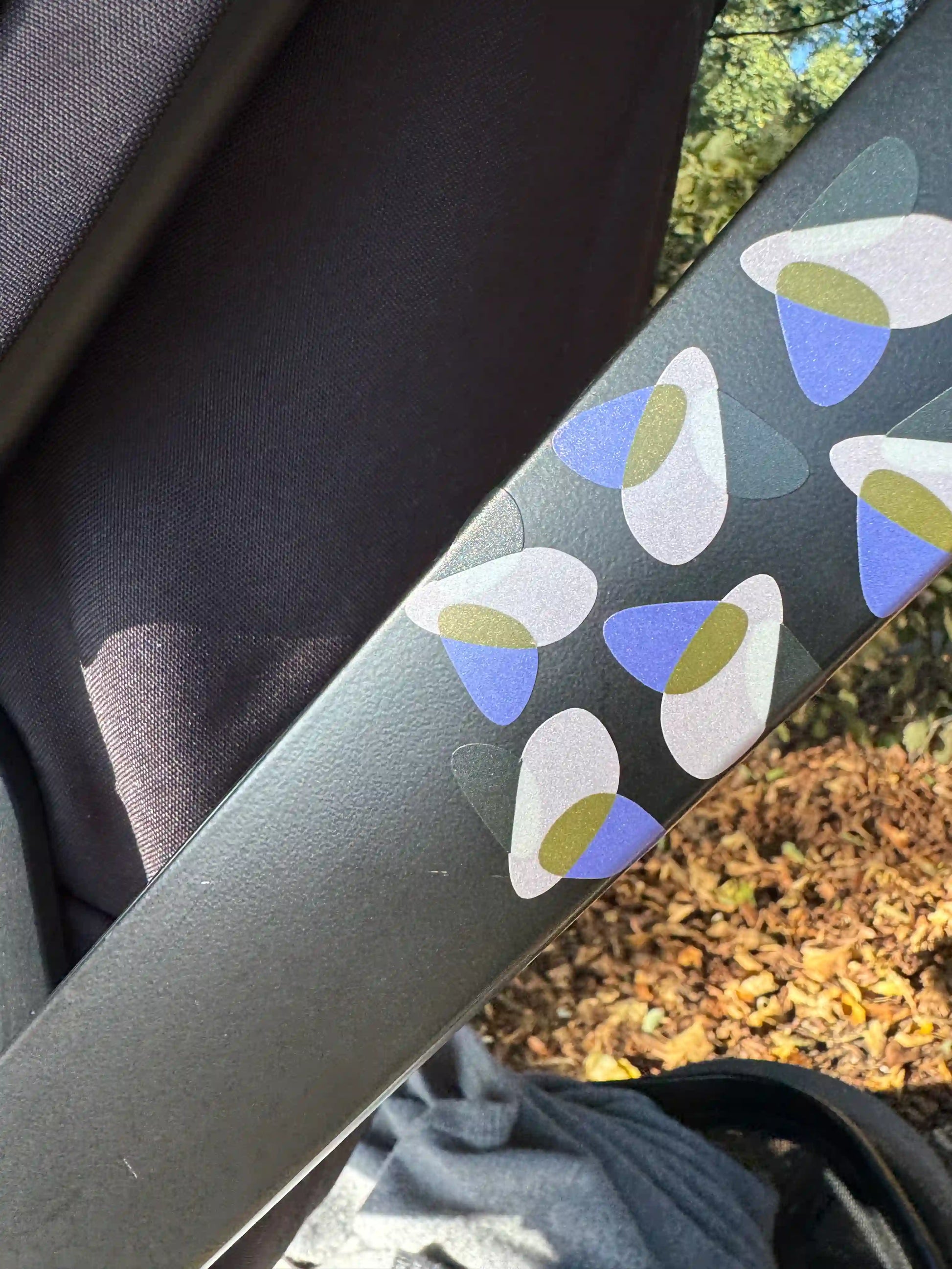 Glowbug Originalbug reflektierende Sticker auf Kinderwagenrahmen im Sonnenlicht — modernes Design für bessere Sichtbarkeit und Sicherheit unterwegs